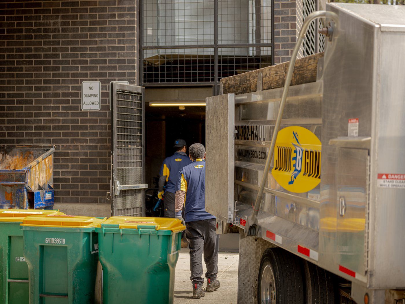 Junk B Gone crew in uniform at a loading dock beside the company truck.