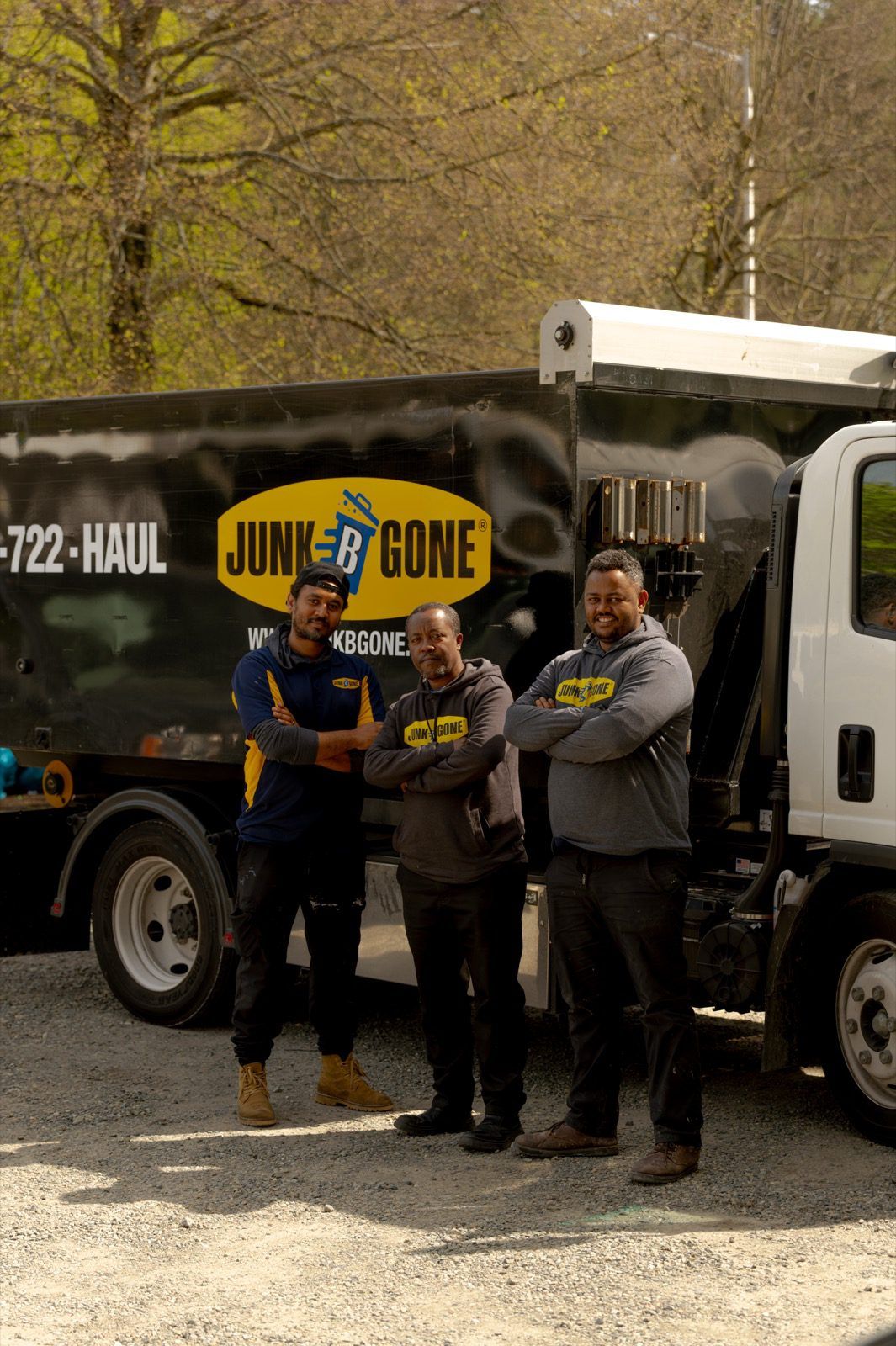 Three Junk B Gone crew members in front of a branded haul truck in Seattle daylight - the same local crews since 1989