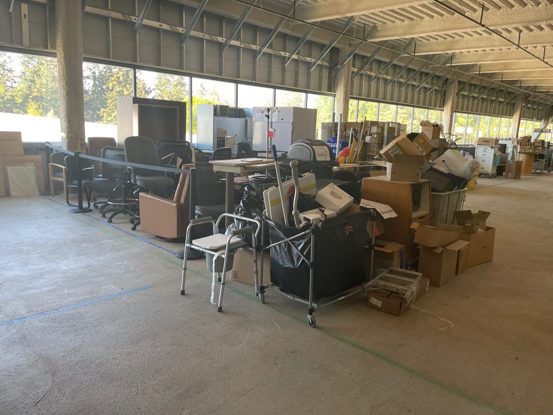 A big open commercial floor staged with rows of office chairs, file cabinets, desks, and boxes that Junk B Gone is clearing out near Seattle