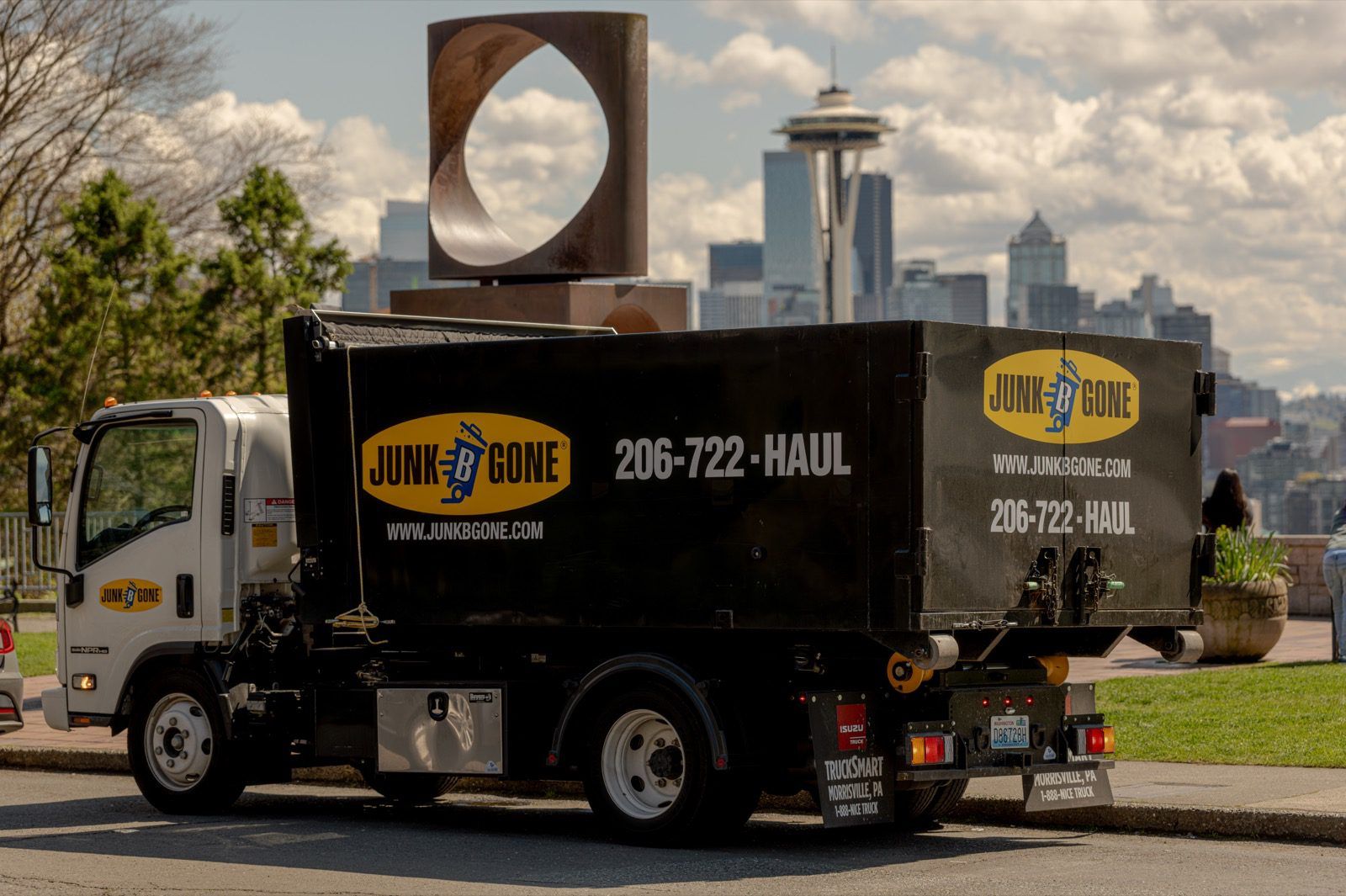 A Junk B Gone branded dump truck staged in front of the Seattle skyline and Space Needle on a commercial junk-removal job