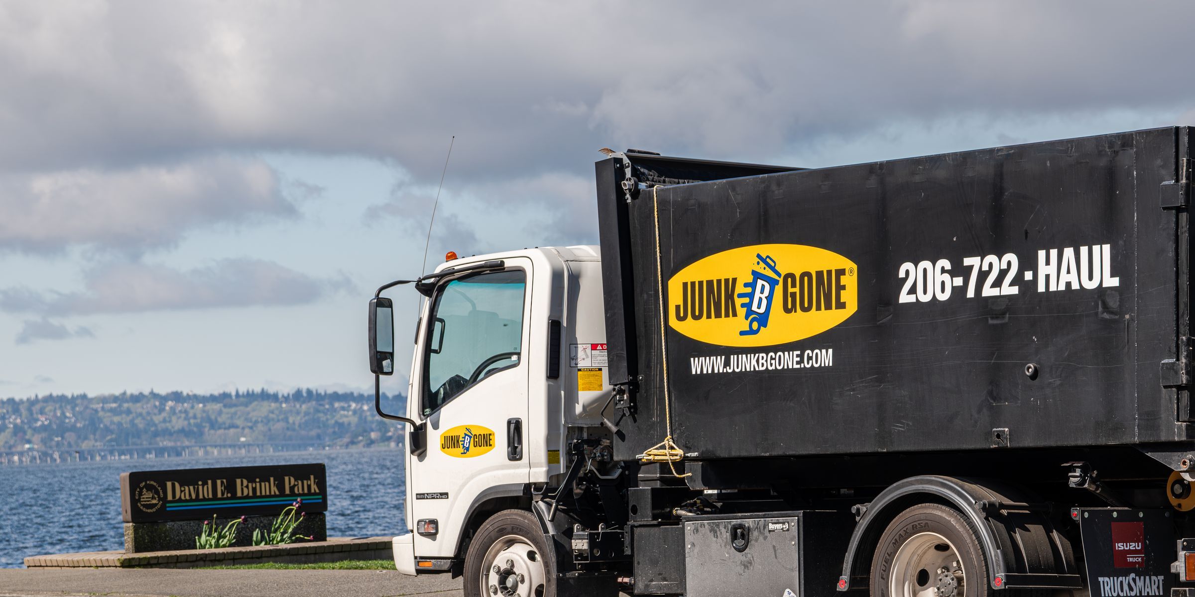 Junk B Gone truck parked beside the David E. Brink Park sign on Lake Washington Boulevard in Kirkland