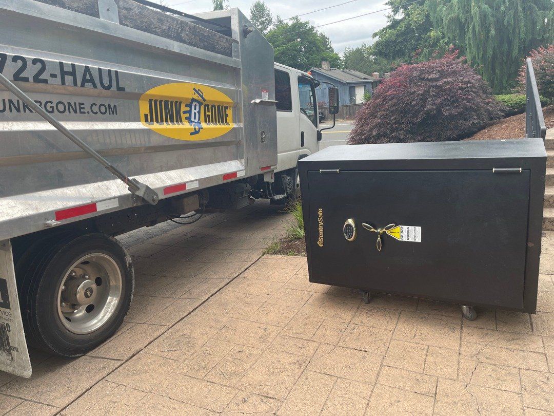 A heavy black safe rolled out to the Junk B Gone truck on a stamped-concrete driveway in Kirkland