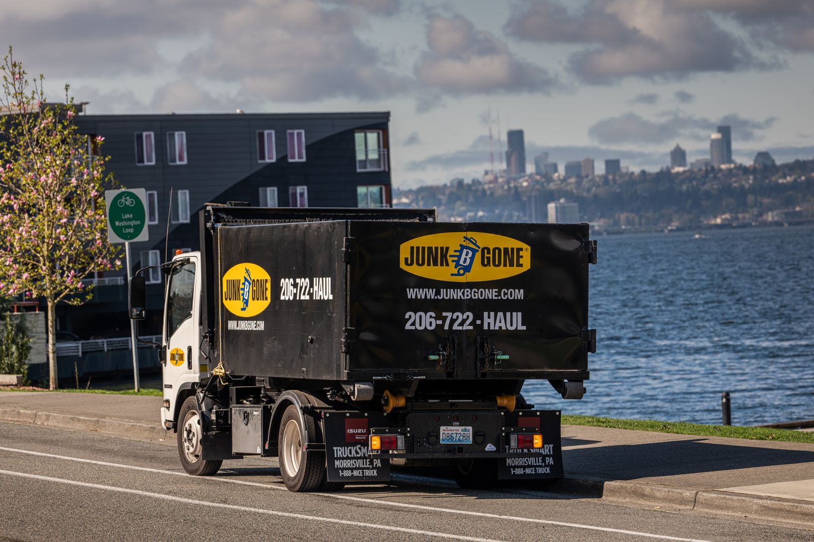 Junk B Gone truck at the curb on Lake Washington Boulevard in Kirkland with the Seattle skyline across the water