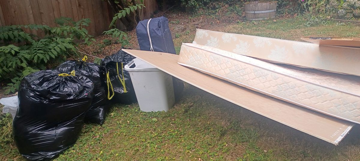 Mattress, box spring and bagged trash ready for pickup in a Phinney Ridge backyard