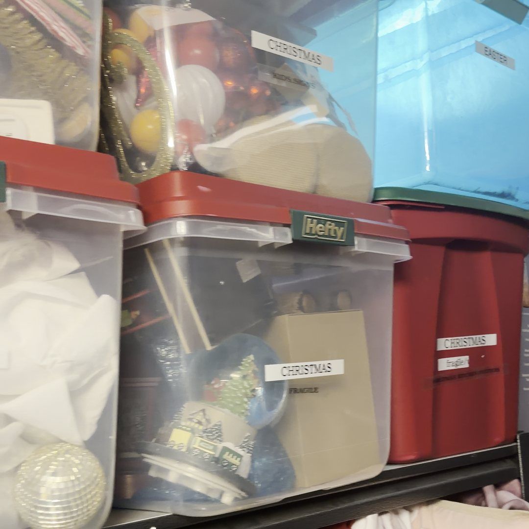 Clear lidded totes labeled Christmas and Easter stacked on garage shelving after a Sort & Haul Day