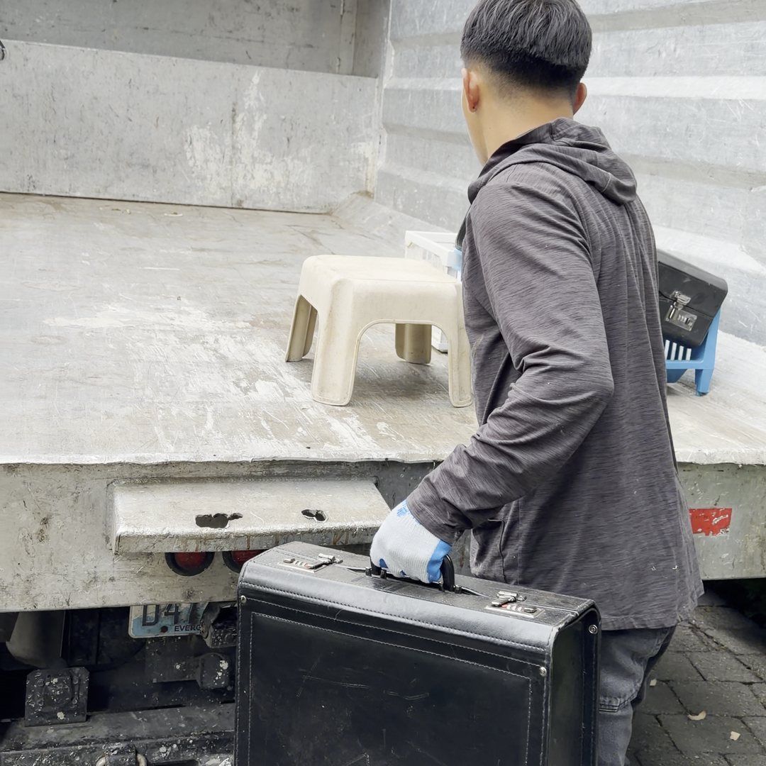 A crew member carrying a black case to the truck to load it by hand