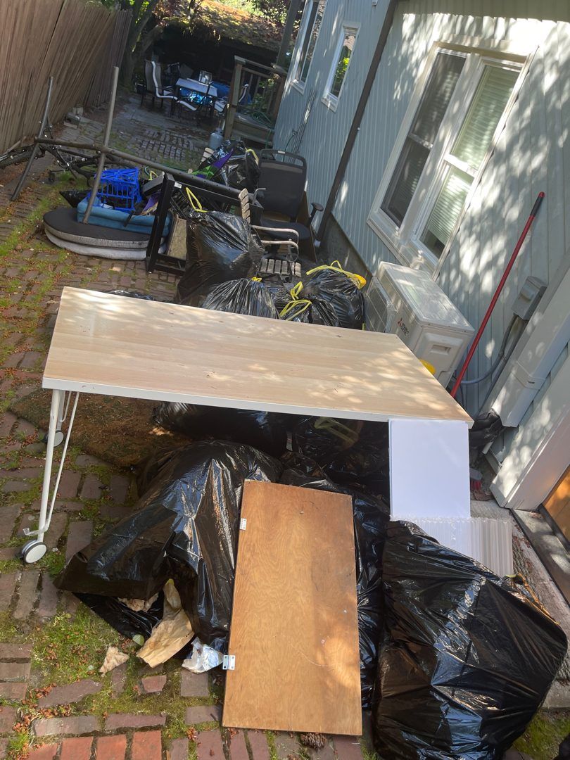 Table, wood panels and bagged junk ready for pickup in a Wallingford side yard