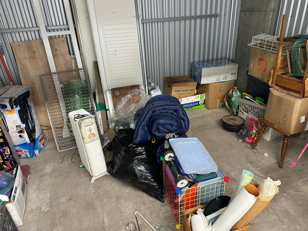 Boxes, trash bags, chairs and a table in a Seattle storage unit before the cleanout
