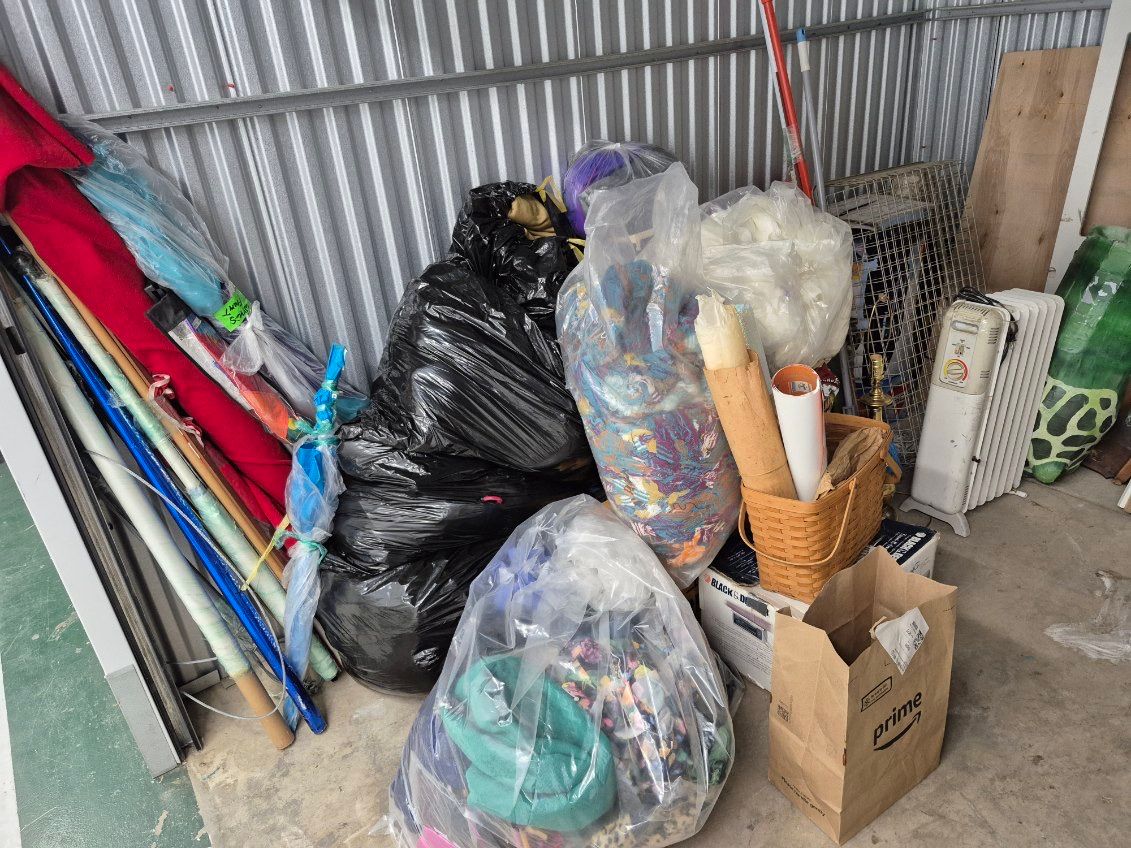 Trash bags, clothing, toys and an old appliance inside a Seattle storage unit before the cleanout