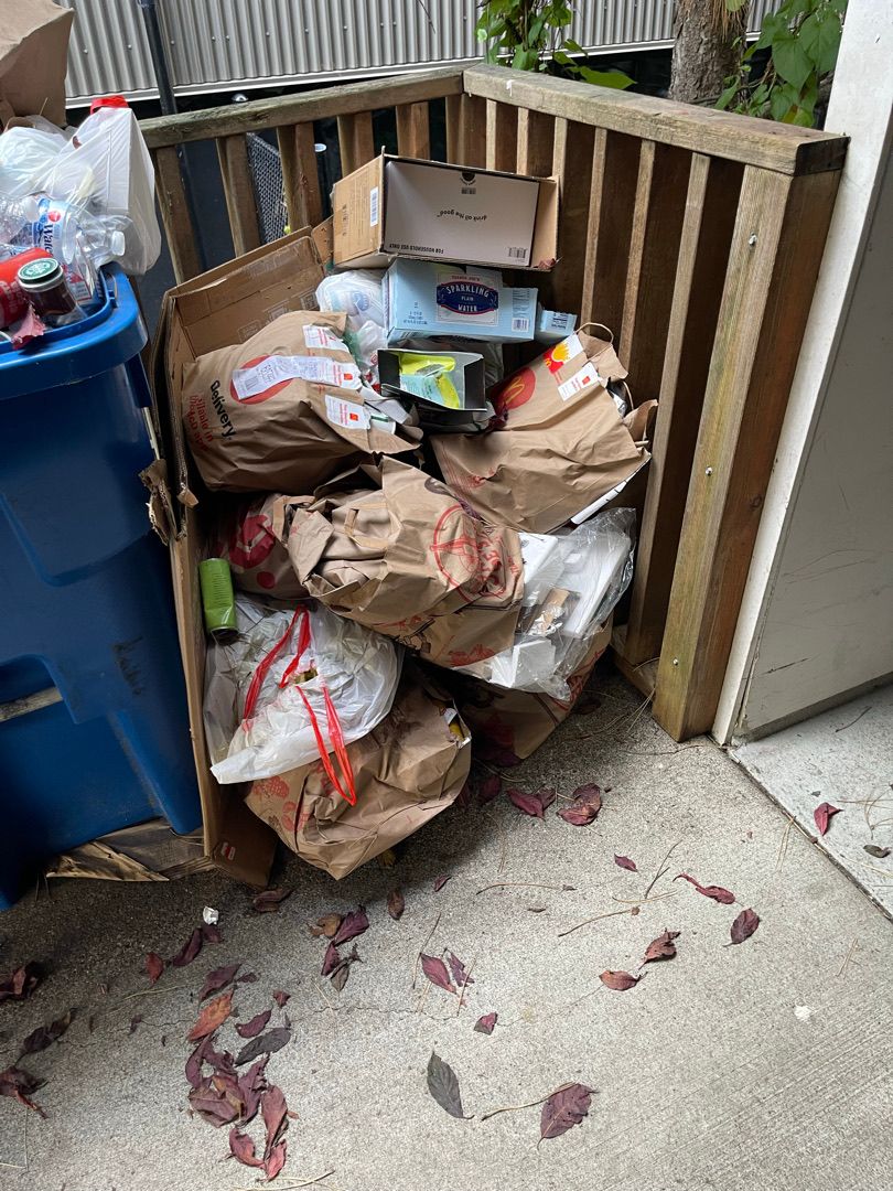 Trash bags, boxes, mixed household items and kitchenware filling a space in a Seattle rental before junk removal