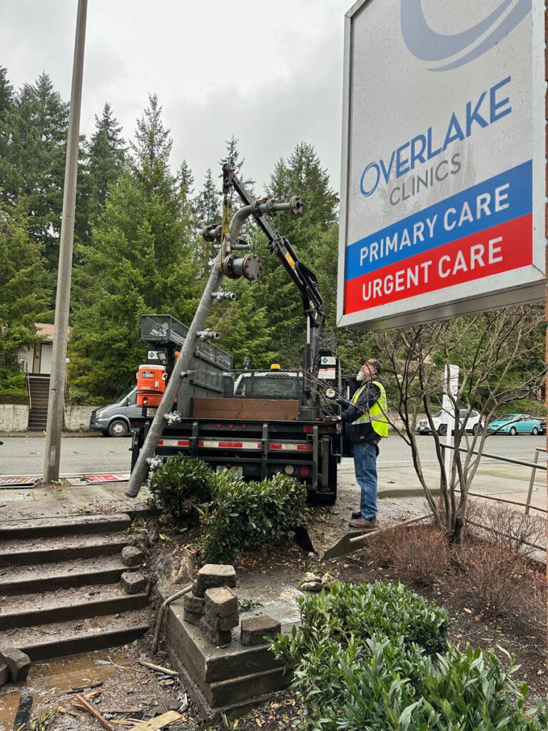 Lifting the natural gas pipe from the wreckage into the back of our truck next to an Overlake Clinic sign.