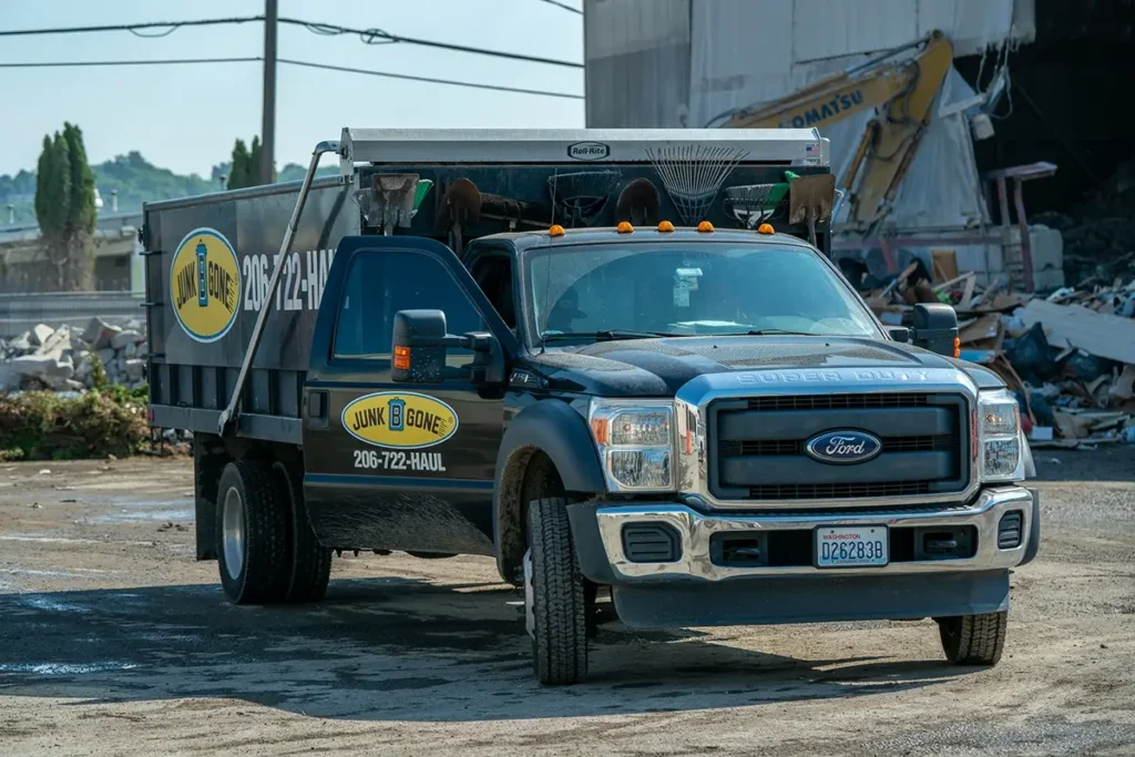 Junk B Gone truck at a recycling center with rear door open, showing responsible disposal