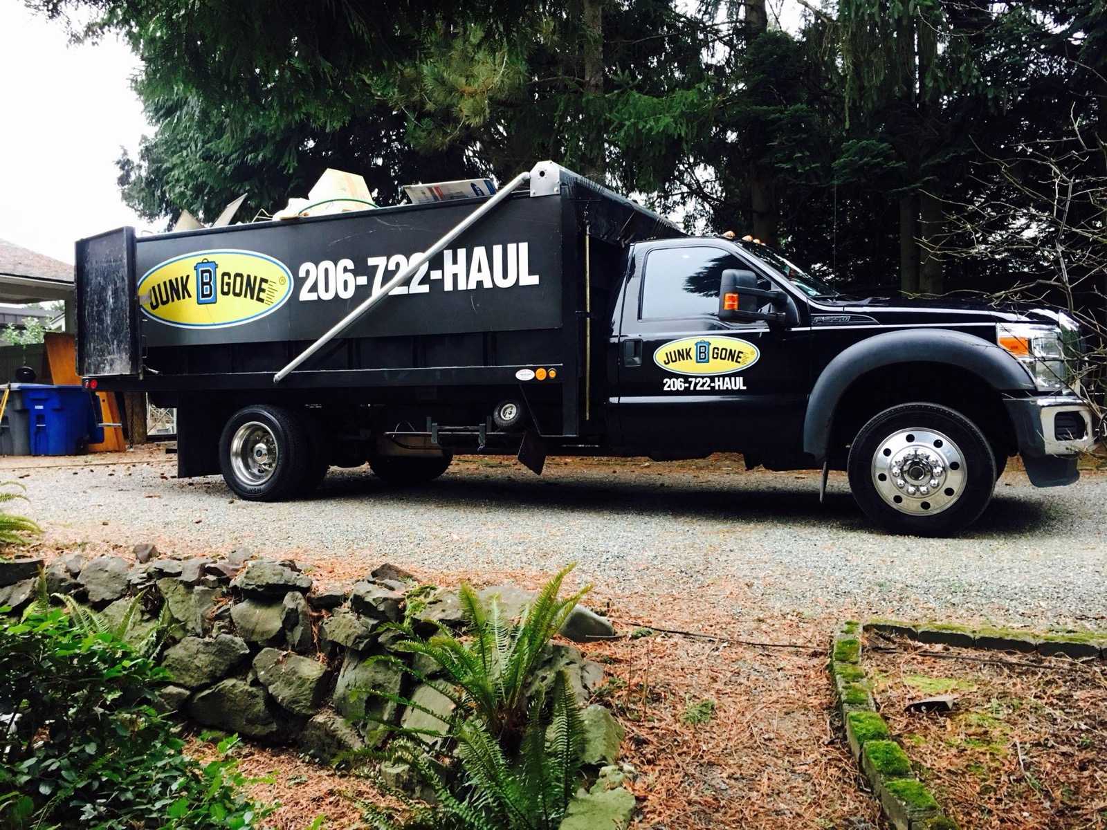 Junk B Gone branded truck — full side profile with 206-722-HAUL phone number visible, parked at a Seattle residential job