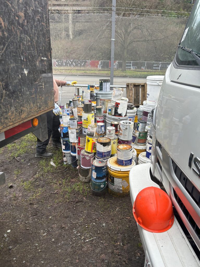 Stacks of paint cans being loaded by Junk B Gone crew for responsible disposal