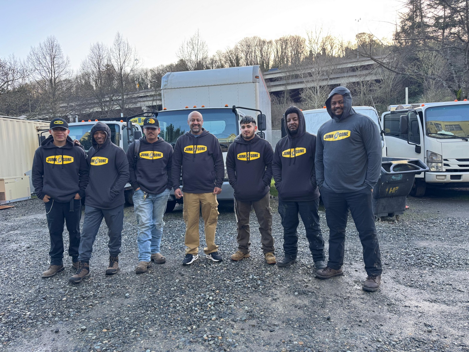 Junk B Gone crew of seven team members in branded hoodies at the Seattle yard with trucks